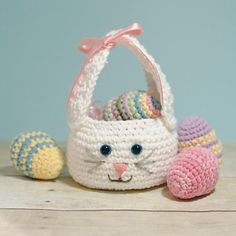 a small crocheted basket with an easter bunny and eggs on the table next to it