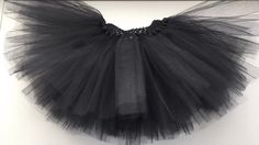 a black tutu skirt hanging on the wall in front of a white framed photo