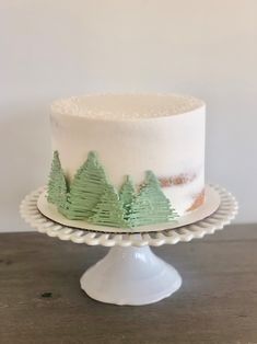 a white cake with green trees on it