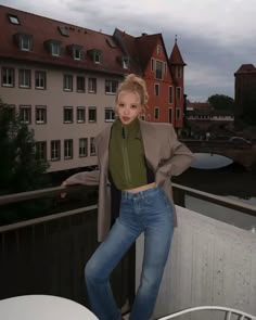 a woman standing on top of a balcony next to buildings