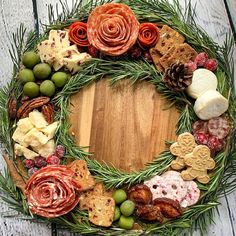 a wreath made out of different types of food on a wooden table with pine cones and berries