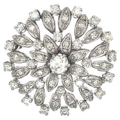 This exquisite vintage brooch from the 1960s is a true representation of timeless elegance. Crafted in luxurious 18k white gold, the piece showcases a breathtaking floral design adorned with dazzling diamonds. At the heart of this brooch sits a captivating transitional cut round diamond weighing approximately 0.40 carats. This center stone boasts a bright I color and exceptional VS1 clarity rating, allowing it to sparkle with brilliance and fire. Radiating outwards from the center are four rows of meticulously arranged diamonds, creating the intricate petal formation of the flower motif. These diamonds are comprised of 48 round brilliant-cut stones, collectively weighing an impressive 1.50 carats. The quality of these diamonds is remarkable, showcasing a range of H to J colors and VS2 clar Diamond Flower Brooch, Flower Motif, Diamond Flower, Vintage Brooch, The 1960s, Precious Gemstones, Vintage Diamond, Flower Brooch, Vintage Brooches