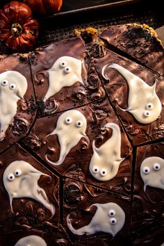 chocolate with white icing and spooky ghost faces on it, surrounded by pumpkins