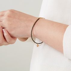 A delicate layered friendship bracelet featuring gold plated chain, teeny tiny beads in white or black and a gold moon charm at the centre. This minimalist but intricate gold chain bracelet is hand-threaded with miniscule glass beads and a gold plated crescent-moon charm. Hanging alongside the tiny beaded bracelet is a dainty gold plated chain, all fixed under the one clasp. The layered look made easy! This simple monochrome bracelet comes in a choice of white beads or black beads. ALSO AVAILABL Adjustable Everyday Bracelet With Moon Charm, Adjustable Moon Charm Bracelet For Everyday, Elegant Everyday Bracelets With Moon Charm, Black Friendship Bracelet, White Bead Bracelet, Simple Beaded Bracelets, White Beads Bracelet, Minimalist Earrings Gold, Friendship Bracelets With Beads