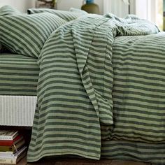 a bed covered in green and white striped sheets