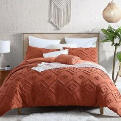 a bed with an orange comforter and pillows