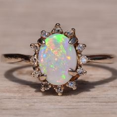 an opal and diamond ring sitting on top of a wooden table