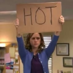 a woman holding up a sign that says hot