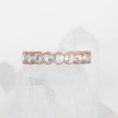 a rose gold wedding band with white stones on the inside and outside, sitting on top of a crystal rock