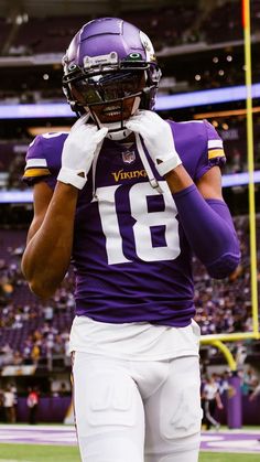 a football player wearing a uniform and holding his hands to his face while standing on the field