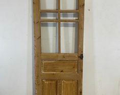 an old wooden door with glass on the top and bottom panel, against a white wall