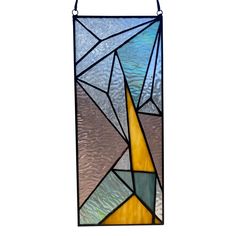 a stained glass window hanging from the side of a white wall with blue, yellow and green colors