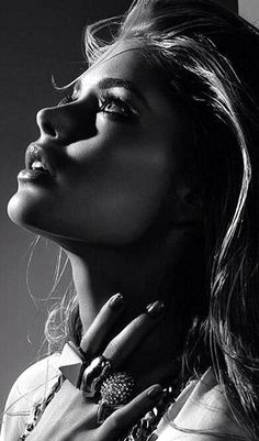 a black and white photo of a woman's face with jewelry on her neck