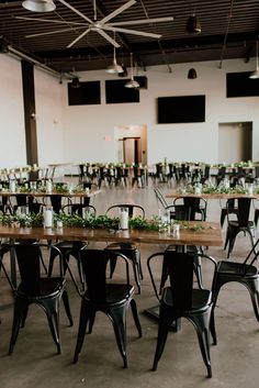 tables and chairs are set up for an event with greenery on the table top