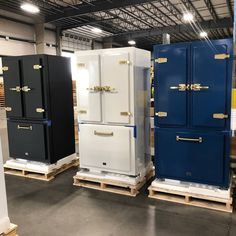 several different colored refrigerators on pallets in a warehouse