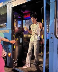 a man standing on the side of a bus with his hand out to another person