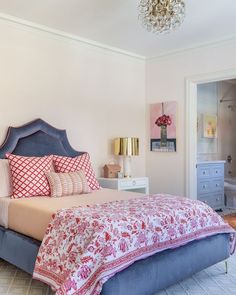 a bedroom with a bed, dresser and chandelier