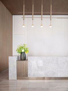 a white marble counter with a plant in the center and four lights hanging above it