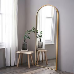 a mirror sitting on top of a wooden table next to a vase filled with flowers