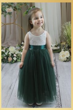 Hunter Green Flower Girl Dress in Sleeveless Fairytales do come true in our full length lace back dress in hunter green. This classic design is so sweet, featuring a low back lace bodice with scalloped edges and a layered tulle skirt that is extra full and dreamy. Ideal for that pretty flower girl dress, birthday party dress or special occasion. Dress Features A soft white bodice, made of stretchy lace with a "V" shaped on the back, edged with delicate lace A cotton liner under 2 layers of soft tulle that won’t itch your princess. Dress length of mid-calf to floor depending on child’s height Sashes are not attached and come in a variety of options from a plain sash, jewels/rhinestones and flowers Large Floral Sash comes in Navy, ivory, creams, and white flowers. Attached to a navy sash. Th Green Flower Girl Dress, Green Flower Girl Dresses, Lace Back Dress, Sleeveless Flower Girl Dresses, Dress Birthday Party, Lace Back Dresses, Ivory Flower Girl, Green Tulle, Ivory Flower Girl Dresses