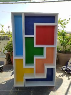 a multicolored box sitting on top of a cement floor next to a potted plant