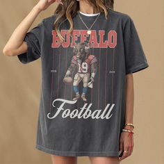 This retro Buffalo football t-shirt features a vintage illustration of a Buffalo holding a football dressed as a football player. This tee is the perfect gift for football fans or anybody who loves a good buffalo and football. This shirt is not associated with any team or league and is simply a piece of sports memorabilia for football fans in buffalo. This retro pinstripe football graphic t-shirt is an awesome piece of buffalo football merch for any sports fan or member of the mafia. This retro Football Season Sports Fan T-shirt With Screen Print, Sports Fan T-shirt For Football Season With Screen Print, Football Season Team Spirit Graphic T-shirt, Team Spirit Football Season Graphic T-shirt, Letter Print T-shirt For Football Season Streetwear, Football Season Fan Merchandise T-shirt, Screen Print T-shirt For Football Season, Football Season Sports T-shirt With Sublimation Print, Football Season Sports Event T-shirt With Sublimation Print