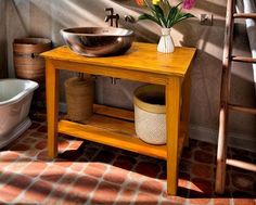 a wooden table topped with a bowl next to a bath tub filled with water and flowers