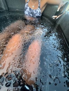 a woman is sitting in the water with her feet up on the edge of an open tub