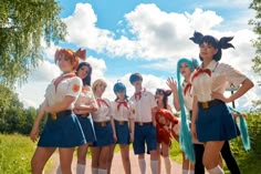 a group of young women standing next to each other on a dirt road with trees in the background