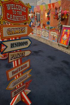 a street sign in front of a carnival with many signs pointing to different places and destinations