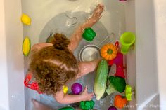 a woman in a bathtub filled with toys and water drops from the faucet