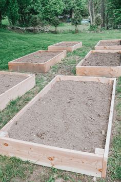 several wooden raised garden beds with dirt in the middle and grass on the other side