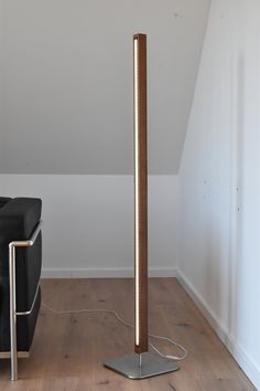 a lamp that is on top of a wooden floor next to a black couch in a room