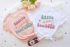 two t - shirts that say dazed and engaged next to a bottle of booze