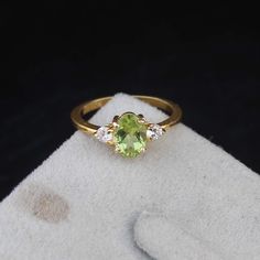 a ring with an oval cut green stone surrounded by three small white diamonds on a black background