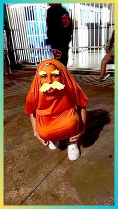 a person in an orange outfit with a fake moustache on their face