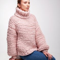 a woman sitting on top of a stool wearing a pink sweater