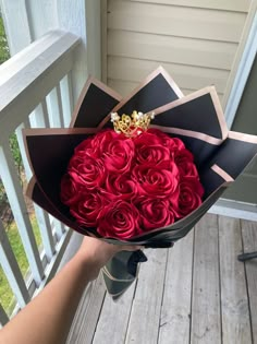 a hand holding a bouquet of red roses on a porch railing with someone's hand