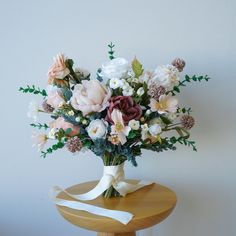 a bouquet of flowers sitting on top of a wooden table next to a white wall