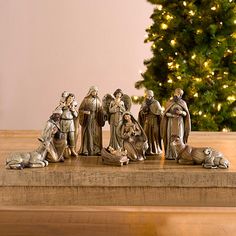 a group of figurines sitting on top of a wooden table next to a christmas tree