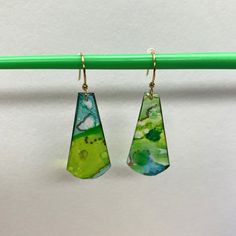 two green and blue earrings hanging from a hook