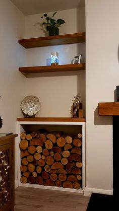 a fireplace with wood stacked on top of it and some shelves in the corner behind it