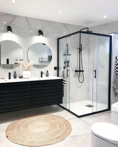 a modern bathroom with black and white fixtures, round mirrors, and marble countertops