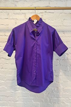 This purple blouse is a versatile and chic top that adds a fresh pop of game day color to any outfit. Whether dressed up or down, it is the perfect addition to your wardrobe. Crisp purple-hued cotton Oversized fit (Recommend sizing down, see fit notes below) Exaggerated classic cuff Ruffled stand-up collar Button front Purple Blouse, Romper And Jacket, Chic Top, Ruffle Shirt, Jumpsuit Jacket, Cami Tanks, Orange And Purple, Scarf Hairstyles, Oversized Fits