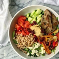 a white bowl filled with lots of different types of food on top of a table