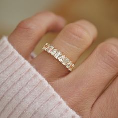 a woman's hand with a gold ring on top of her finger and the band has five stones in it