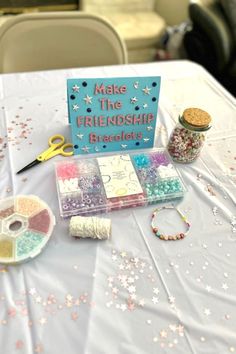 a table topped with lots of crafting supplies on top of a white table cloth