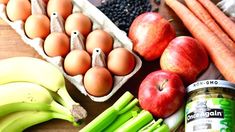 an assortment of fruits, vegetables and eggs on a wooden table with a can of soda