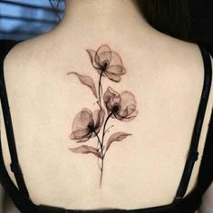 the back of a woman's shoulder with three flowers on her left and one flower on her right side