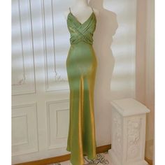 a mannequin wearing a green dress in front of a white wall